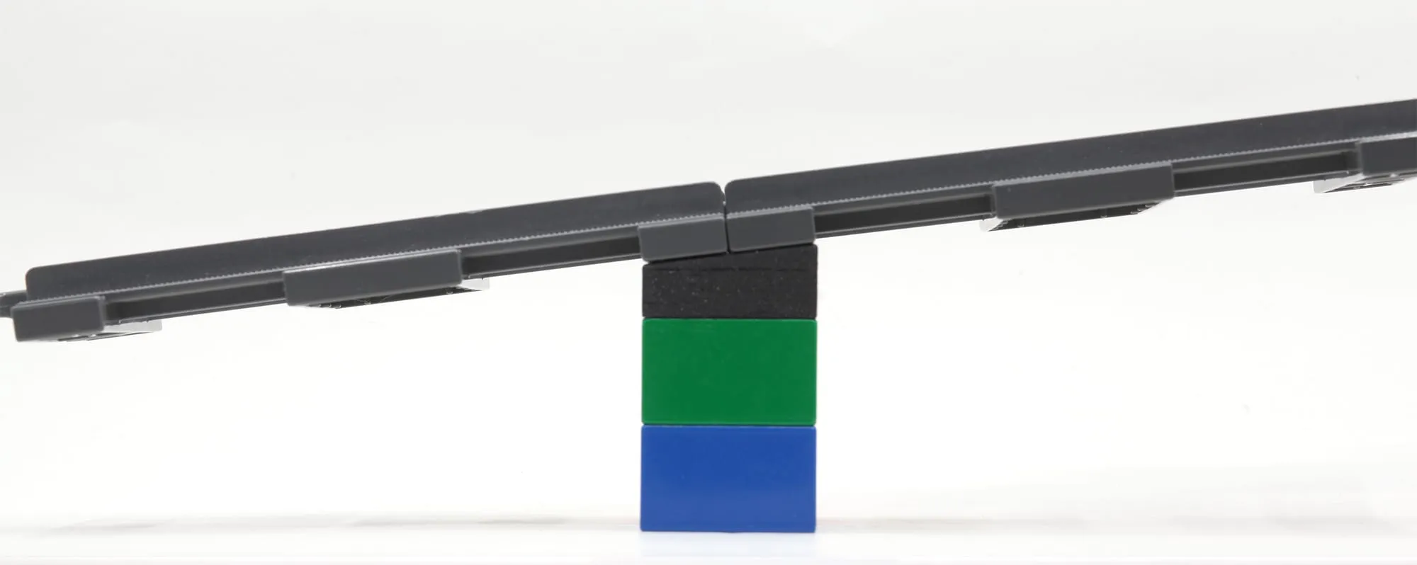 Rails de train DUPLO inclinés en pente, posés sur une brique penchée noire empilée sur des briques verte et bleue