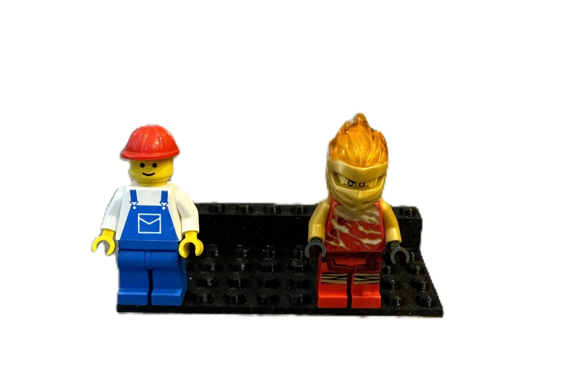 Support noir à plots portant deux figurines, l’une avec un casque rouge, sur fond blanc