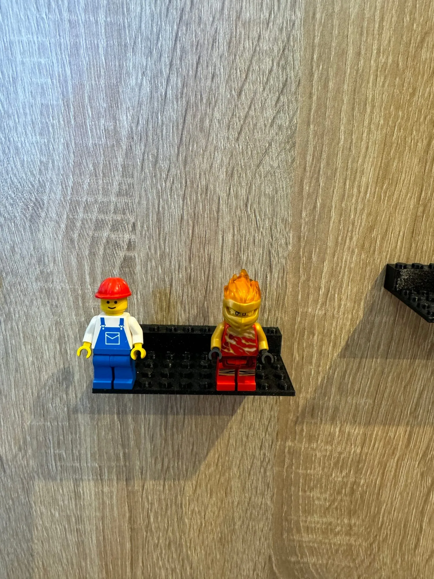 Support noir fixé au mur portant deux figurines