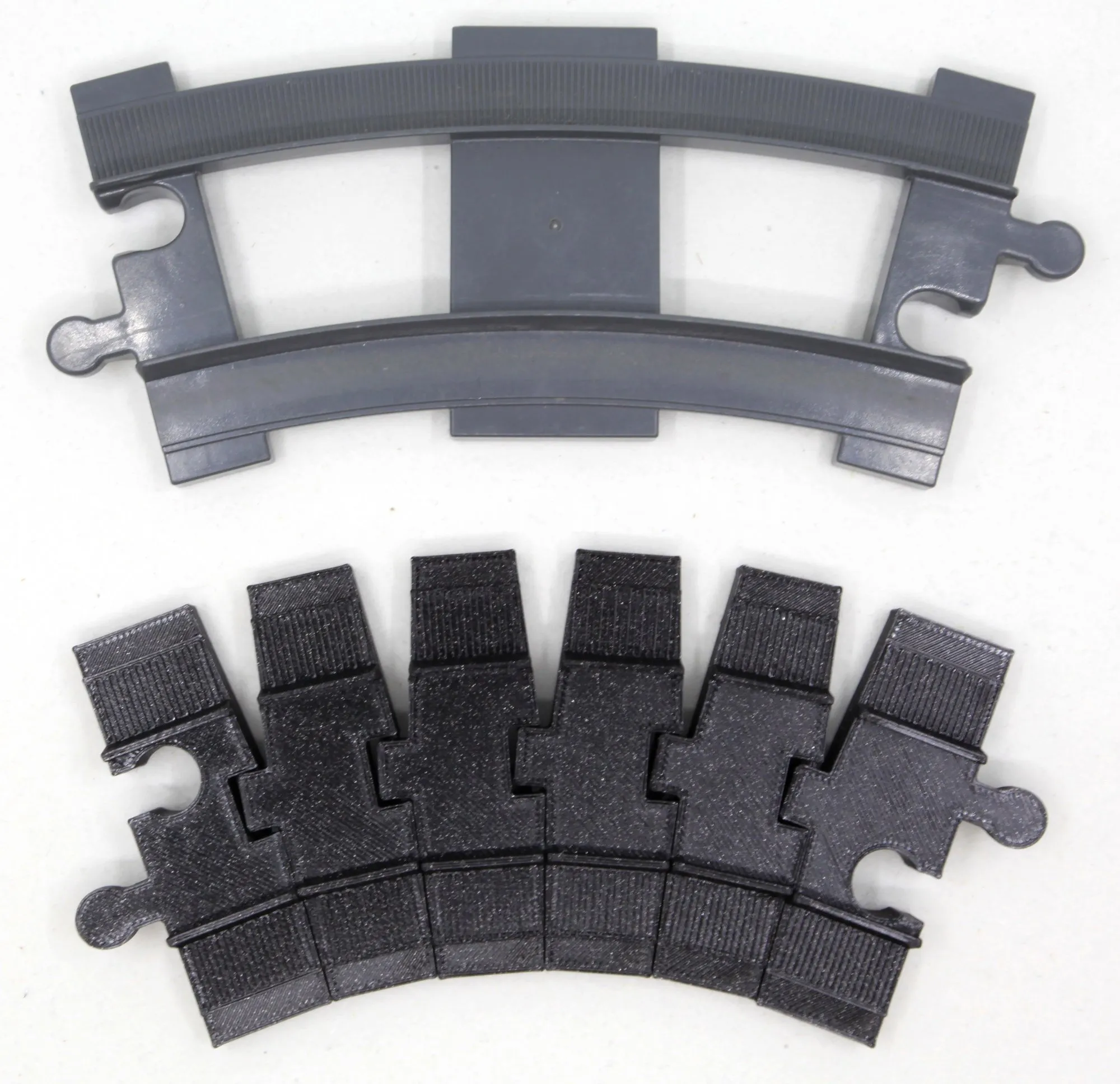 Rail courbe DUPLO gris au-dessus d’un rail flexible noir plié selon la même courbure