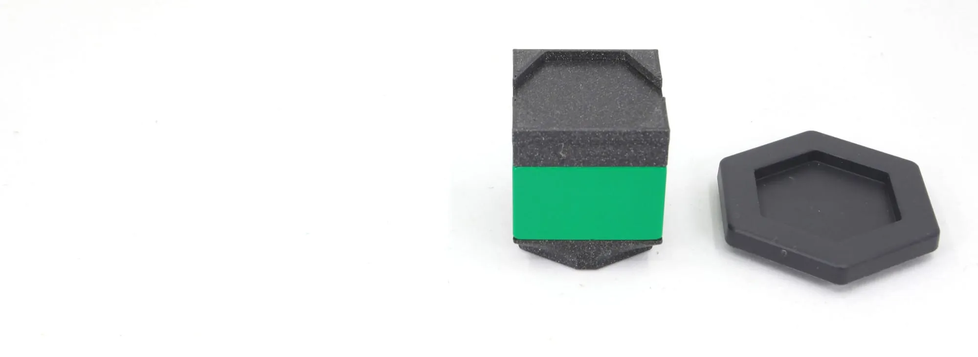 Adaptateur haut posé sur une brique DUPLO verte, à côté d’un adaptateur hexagonal noir