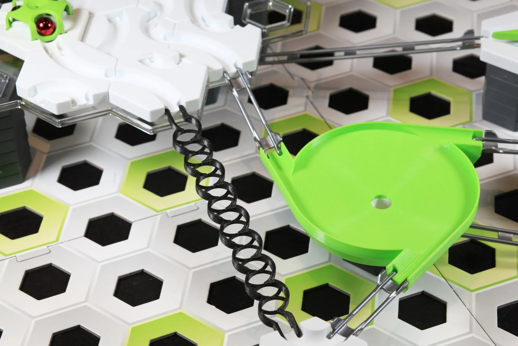 Rail zigzag noir passant près d’une toupie entonnoir verte dans un circuit GraviTrax